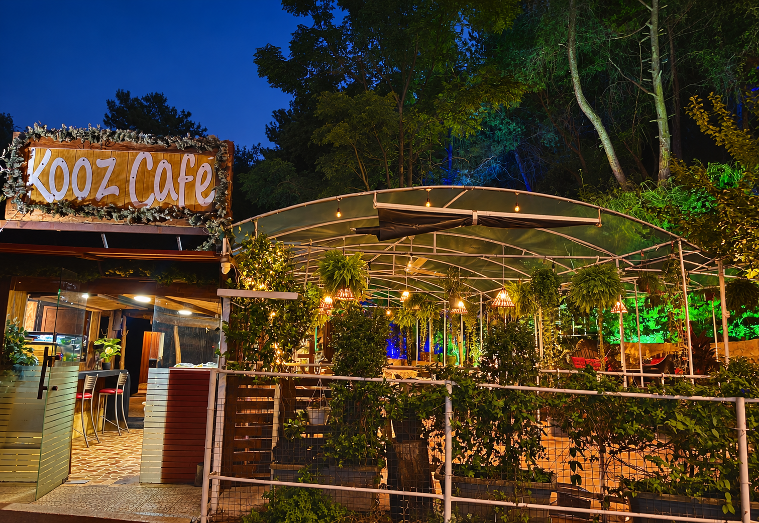 Kooz Café’s garden entrance and sign illuminated at dusk